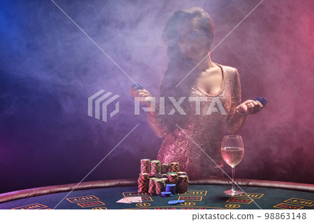 Brunette girl with a perfect hairstyle and bright make-up is posing with gambling chips in her hands. Casino, poker. Brunette girl with a perfect hairstyle and bright make-up is posing with gambling chips in her hands. Casino, poker. 98863148