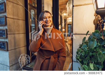 Young happy woman talking on the phone in the street Young happy woman talking on the phone in the street 98863471