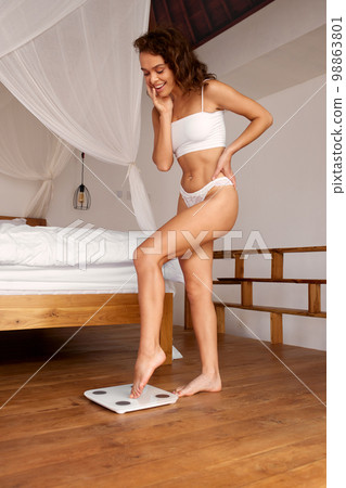 Woman Diet. Happy Woman Measuring Body Weight. Woman Standing On Weighing Scale 98863801