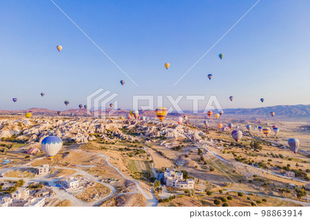 Colorful hot air balloons flying over at fairy chimneys valley in Nevsehir, Goreme, Cappadocia Turkey. Spectacular panoramic drone view of the underground city and ballooning tourism. High quality Colorful hot air balloons flying over at fairy chimneys valley in Nevsehir, Goreme, Cappadocia Turkey. Spectacular panoramic drone view of the underground city and ballooning tourism. High quality 98863914