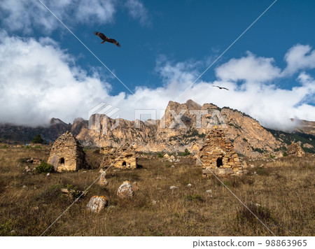 Grave stone city under a big rock. Old stone tomb, a crypt on the top of a mountain. Ossetia region. 98863965