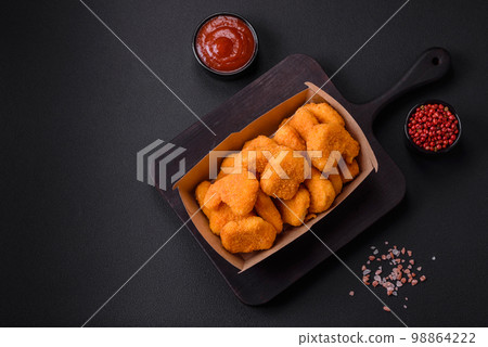 Delicious fresh crispy chicken nuggets on a dark concrete background Delicious fresh crispy chicken nuggets on a dark concrete background 98864222