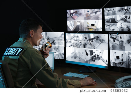 Security guard with portable transmitter monitoring modern CCTV cameras indoors Security guard with portable transmitter monitoring modern CCTV cameras indoors 98865982