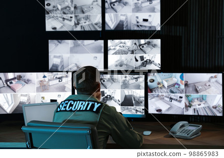 Security guard monitoring modern CCTV cameras in office Security guard monitoring modern CCTV cameras in office 98865983