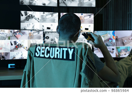 Security guard with portable transmitter monitoring modern CCTV cameras indoors Security guard with portable transmitter monitoring modern CCTV cameras indoors 98865984