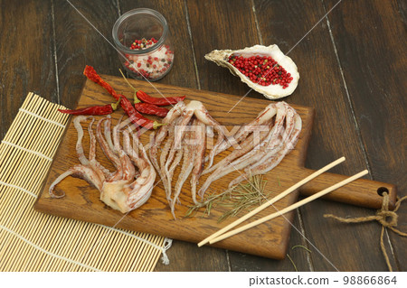 raw squid tentacles with pepper, salt, Japanese sticks on kitchen board ready for cooking closeup photo raw squid tentacles with pepper, salt, Japanese sticks on kitchen board ready for cooking closeup photo 98866864