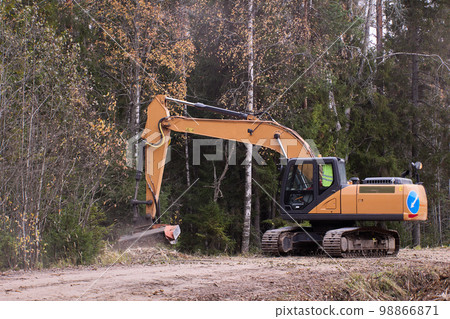 Forestry excavator mulcher doing roadside clearing with mulching machine. Forestry excavator mulcher doing roadside clearing with mulching machine. 98866871