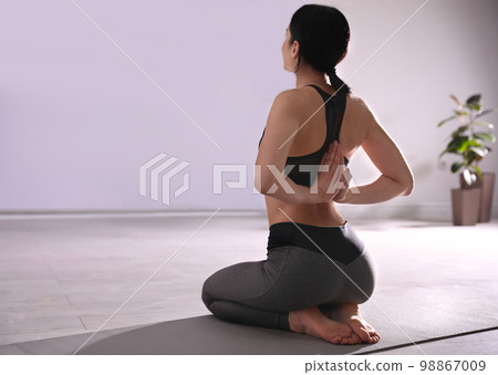 Young woman practicing seiza asana in yoga studio. Vajrasana pose 98867009