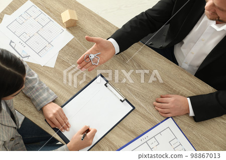 Real estate agent giving key to client at table in office, above view Real estate agent giving key to client at table in office, above view 98867013