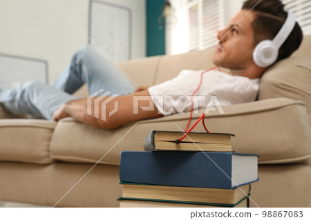 Man with headphones connected to book 98867083