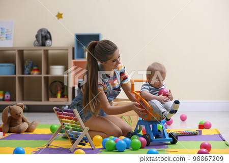 Teen nanny playing with cute little baby at home 98867209