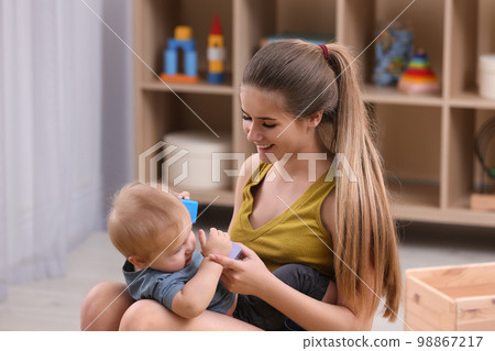 Teen nanny and cute little baby playing with toys at home Teen nanny and cute little baby playing with toys at home 98867217