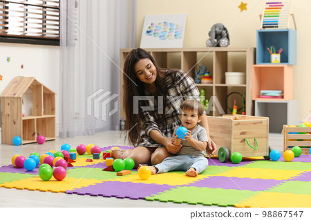 Young nanny and cute little baby playing with toys at home Young nanny and cute little baby playing with toys at home 98867547