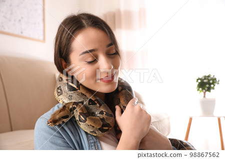Young woman with her boa constrictor at home. Exotic pet Young woman with her boa constrictor at home. Exotic pet 98867562