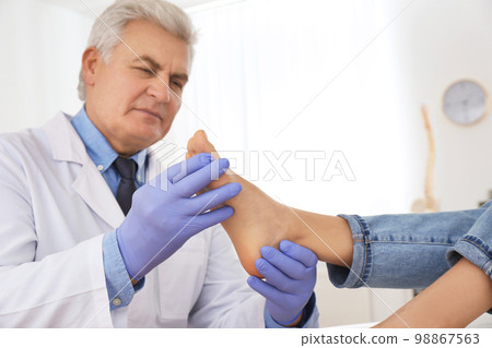Male orthopedist checking patient's foot in clinic Male orthopedist checking patient's foot in clinic 98867563