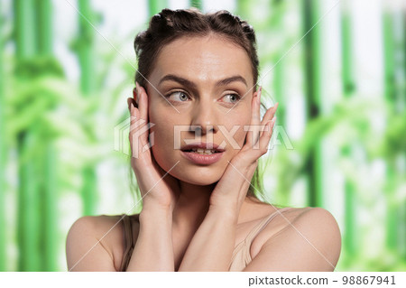 Beauty model holding palms on face, demonstrating fresh skin after cosmetology treatment and looking at side. Beautiful young woman posing with hands on cheeks for skincare product Beauty model holding palms on face, demonstrating fresh skin after cosmetology treatment and looking at side. Beautiful young woman posing with hands on cheeks for skincare product 98867941