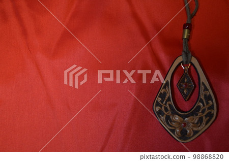 A large cross-shaped pendant made of leather 98868820