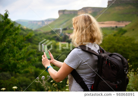Woman hiker uses gps navigator app in smartphone walking in mountain 98868891