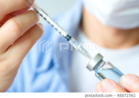 doctor's hand holds a syringe and a blue vaccine bottle at the hospital. Health and medical concepts. 98872562