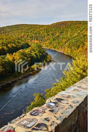 Huge Delaware River in early fall forest next to stone wall with chalk art graffiti 98873328