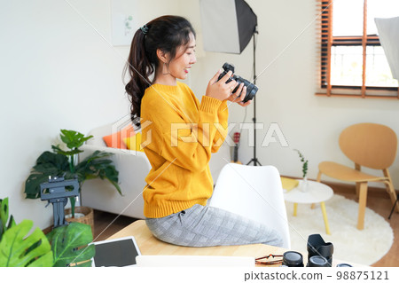 Lifestyle Asia young women photographer and freelance holding a dslr camera in home office. Lifestyle Asia young women photographer and freelance holding a dslr camera in home office. 98875121