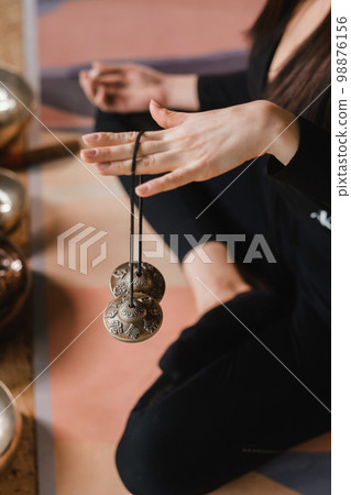 Close-up of a woman's hand holding Tibetan bells for sound therapy. Tibetan cymbals Close-up of a woman's hand holding Tibetan bells for sound therapy. Tibetan cymbals 98876156