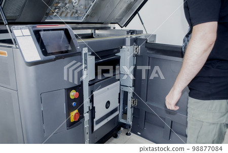 A man worker and a large industrial powder 3d printer in a laboratory in a factory. Multi Jet Fusion. Industrial equipment. New modern 3D printing , additive progressive technology. MJF 98877084
