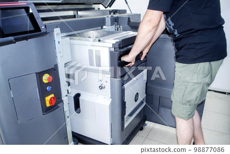 The worker moves the working camera of the 3D printer into the 3D printer. Large industrial 3D printer printing with polyamide powder in a production laboratory. Multi Jet Fusion. Industrial equipment 98877086