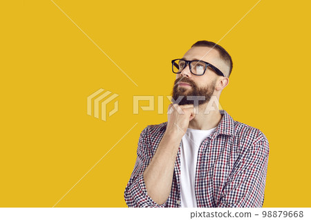 Man in glasses thinking about something and looking away at yellow copy space background 98879668