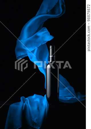 Bottle of red wine and flutters of blue cloth. Bottle of red wine and flutters of blue cloth. 98879872