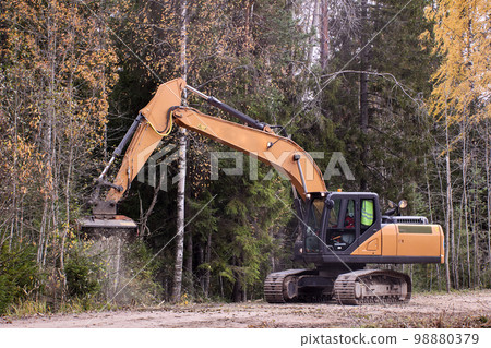 Forestry mulching machine attached to excavator, being used to clear roadside brush. Forestry mulching machine attached to excavator, being used to clear roadside brush. 98880379