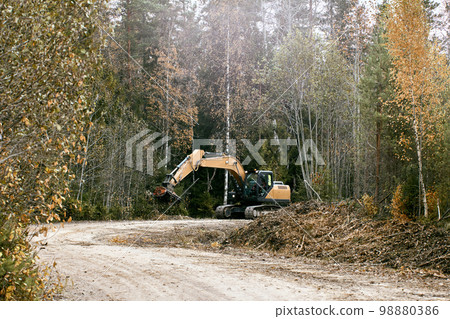 Vegetation removal with excavator forestry mulcher head. Vegetation removal with excavator forestry mulcher head. 98880386