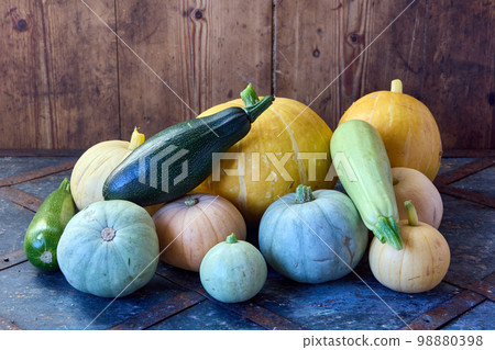 Fresh raw marrows and pumpkins are stacked in pile on wooden table. 98880398