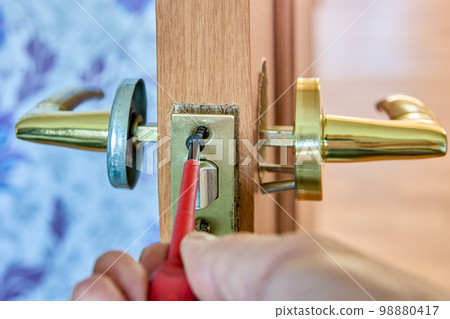 Assembling mechanism of lever door handle, locksmith tightens fixing screw using a screwdriver. 98880417