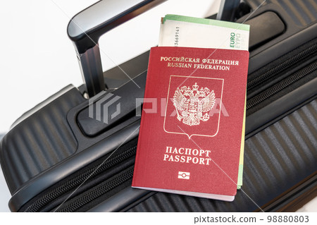Passport with enclosed Euro banknotes on a black suitcase as a symbol of travel Passport with enclosed Euro banknotes on a black suitcase as a symbol of travel 98880803
