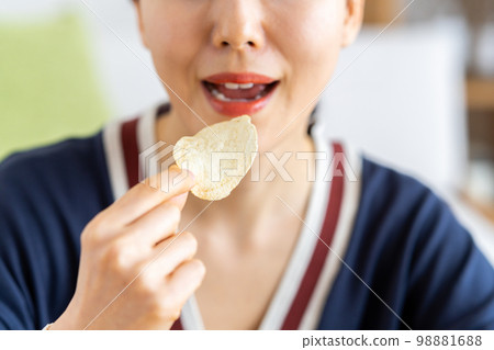 A young woman eating potato chips 98881688