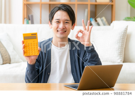 Happy middle-aged man holding a calculator OK 98881784