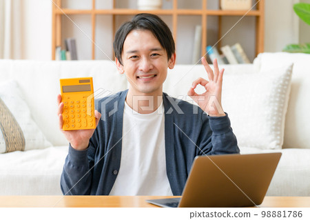 Happy middle-aged man holding a calculator OK 98881786