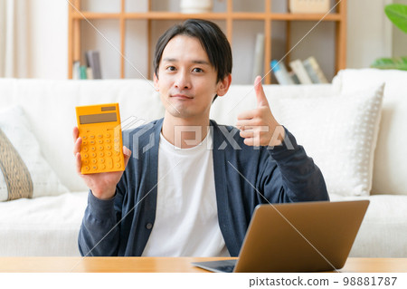 Happy middle-aged man holding a calculator thumbs up Happy middle-aged man holding a calculator thumbs up 98881787