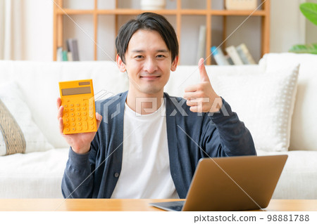 Happy middle-aged man holding a calculator thumbs up Happy middle-aged man holding a calculator thumbs up 98881788