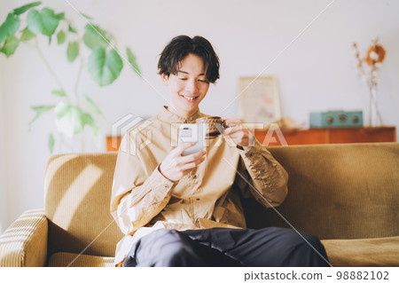 Man looking at smartphone while drinking coffee Man looking at smartphone while drinking coffee 98882102