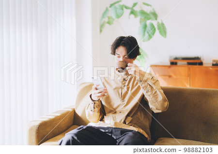 Man looking at smartphone while drinking coffee 98882103