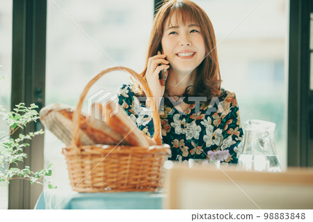 A Japanese woman in her twenties talking on a mobile phone in a cafe 98883848