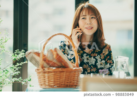 A Japanese woman in her twenties talking on a mobile phone in a cafe 98883849