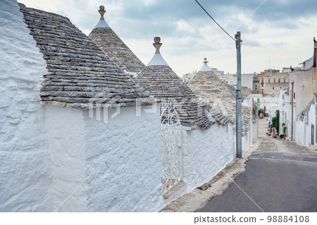 Beautiful town of Alberobello with Trulli houses among green plants and flowers, Apulia region, Southern Italy. 98884108
