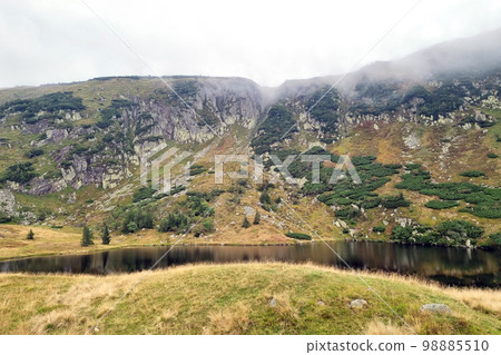 Mountain autumn lake in the mountains. Foggy morning. Mountain autumn lake in the mountains. Foggy morning. 98885510
