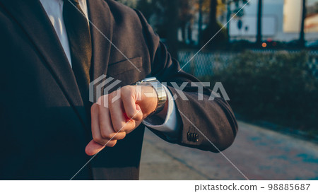 Businessman looks at the smartwatch on his hand. Businessman is checking time on the smartwatch. Close up. Modern gadgets and people concept. Modern communication.. 98885687