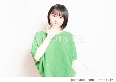 A young woman who hides her mouth with her hand and makes a secret pose 98885916
