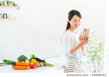 A smiling middle woman standing in the kitchen A smiling middle woman standing in the kitchen 98886065