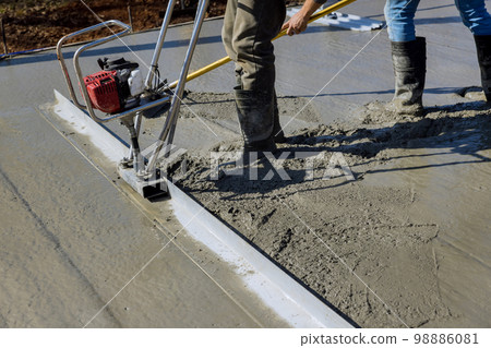 When constructing new driveway machine is used to align fresh concrete on top compacted layer When constructing new driveway machine is used to align fresh concrete on top compacted layer 98886081